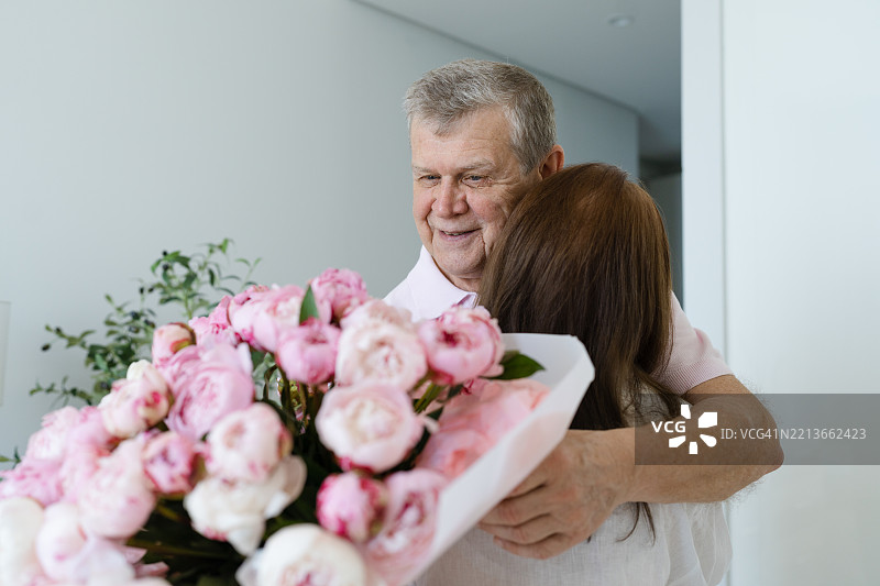 老年夫妇相拥，男人手捧鲜花图片素材