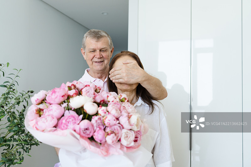 老年男子在家里给女人惊喜，送上一束花图片素材