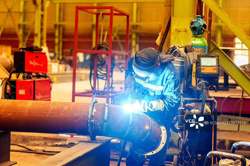 工厂车间内的工业焊工正在使用TIG焊枪焊接管道图片素材