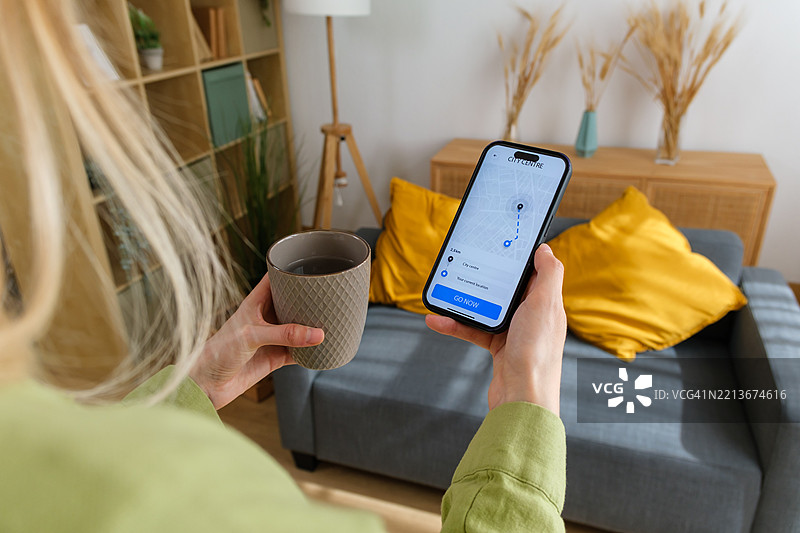 女人在家喝咖啡并使用智能手机上的导航应用程序图片素材