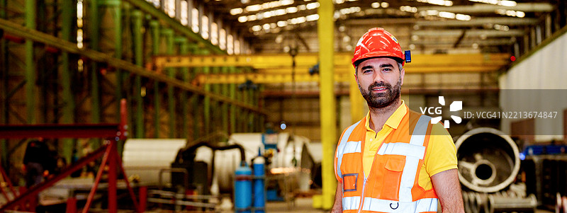 年轻美丽的女工程师在工厂建筑中工作，女性工业建筑工人佩戴安全帽，职业安全与健康图片素材