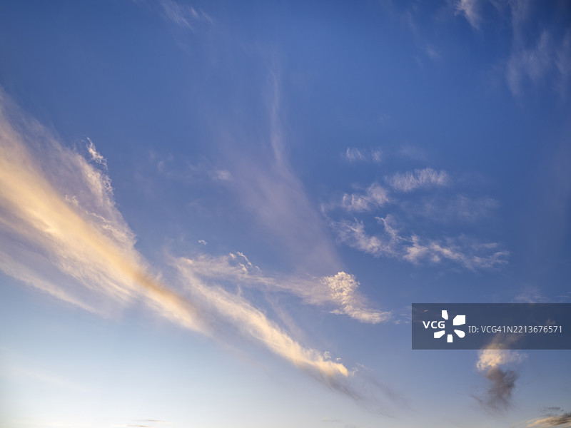 地平线上日落，天空中飘着小巧的粉色高云。图片素材