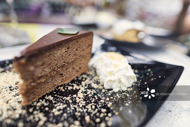 经典维也纳萨赫蛋糕的特写，配有鲜奶油，放在黑色盘子上图片素材