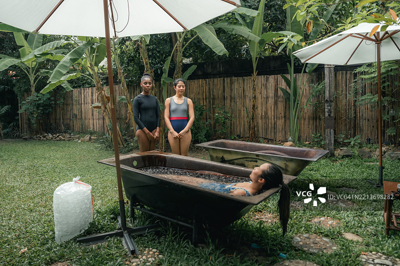女性在进行冰浴疗法的必要步骤，捏着鼻子以屏住呼吸。图片素材