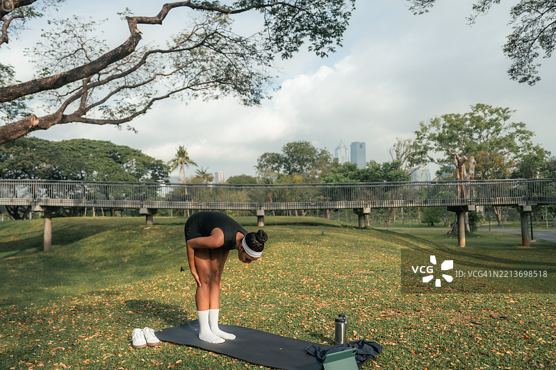 运动女性在公园的瑜伽垫上使用数字平板，浏览教程，选择提升练习的完美课程图片素材