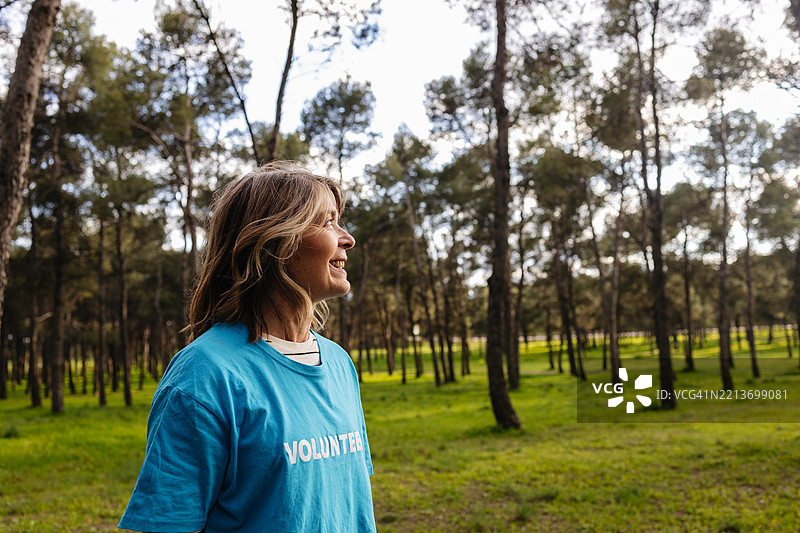 快乐的志愿者微笑着欣赏郁郁葱葱的森林中的植树活动图片素材