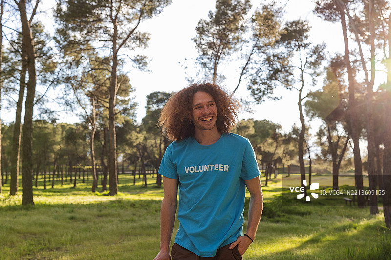 年轻快乐的男性志愿者在阳光明媚的公园里微笑图片素材