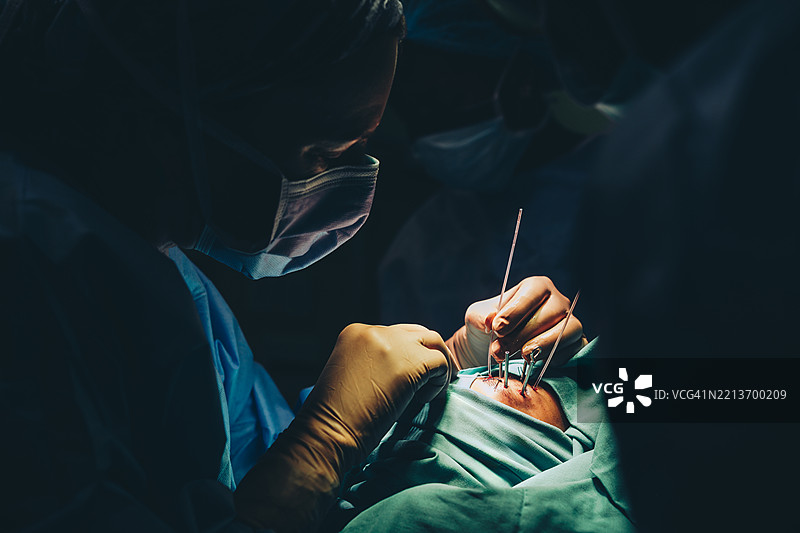 外科医生在昏暗的灯光下进行眼部近距离放疗手术以治疗癌症图片素材