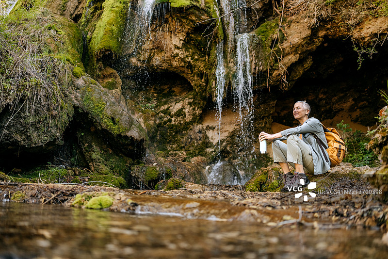 女人在大自然的瀑布旁放松身心图片素材