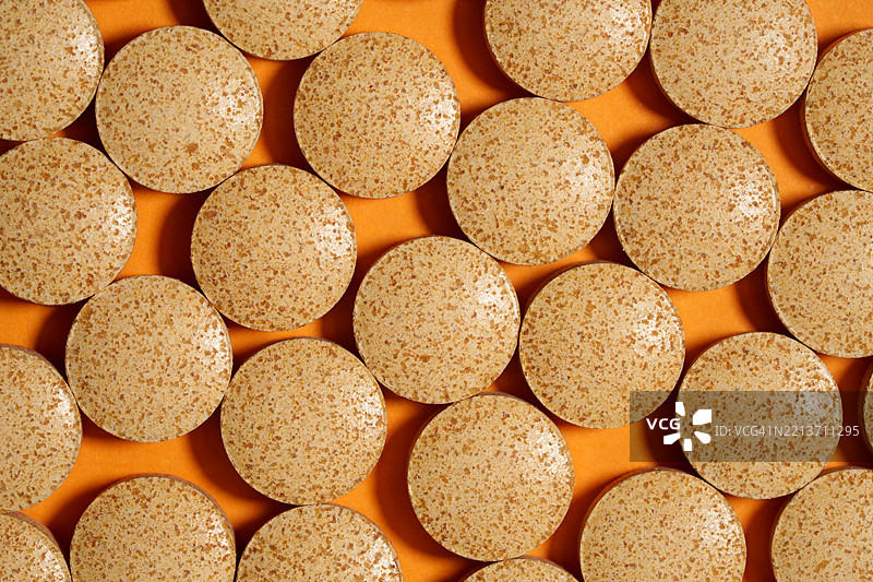 啤酒酵母片在橙色背景上形成纹理图案图片素材