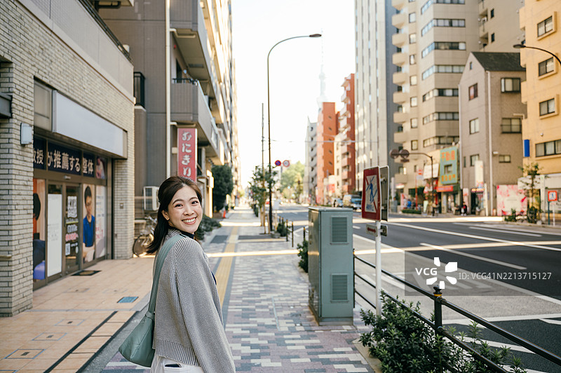 在东京住宅区，一位亚洲Z世代的日本女性在早晨阳光下穿过十字路口。图片素材