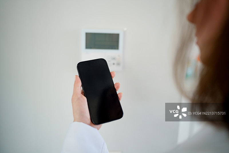女医生通过智能手机远程控制诊所温度图片素材