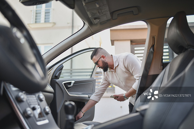 帅气的男性在进入车辆前，在车门里寻找纸巾图片素材