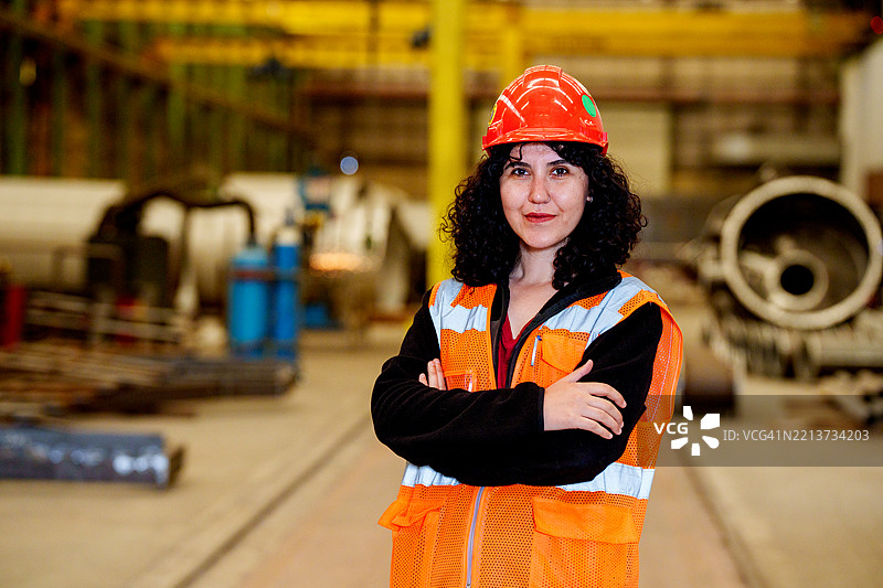 年轻美丽的女工程师在工厂建筑中工作，女工业建筑工人戴着安全帽图片素材
