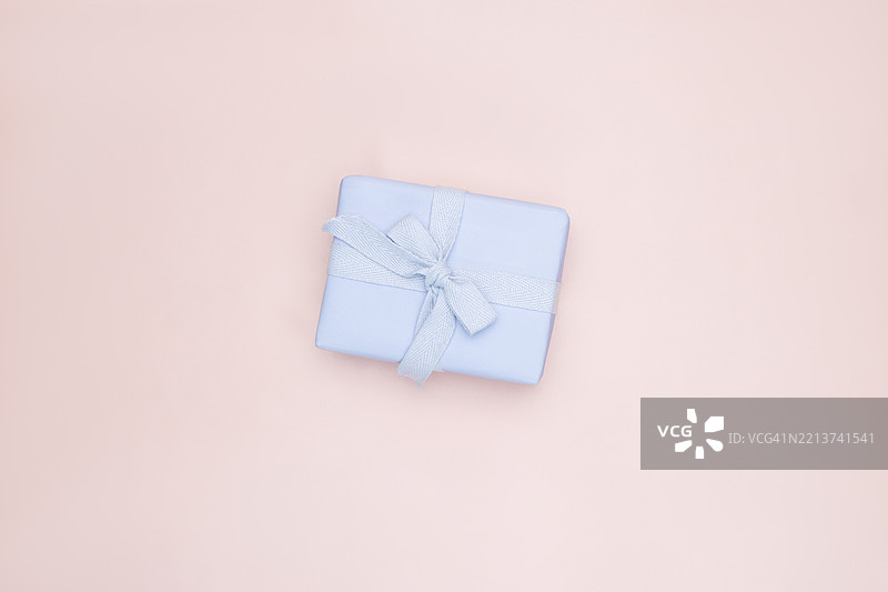 淡粉色丝绸背景上的紫罗兰色礼品盒和蝴蝶结图片素材