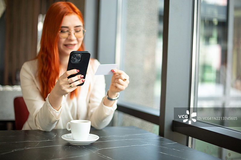 女商人在咖啡馆使用智能手机和信用卡进行在线支付图片素材