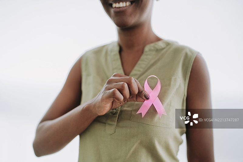 女性手持粉色丝带，背景为单色。图片素材