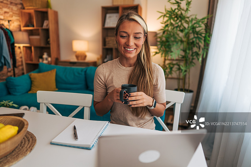 年轻女性在家远程工作并喝咖啡图片素材
