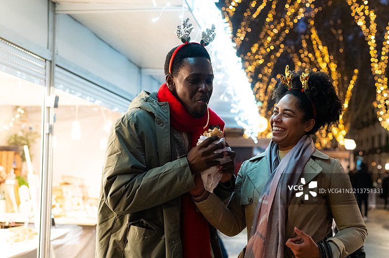 情侣在圣诞市场享受街头美食图片素材