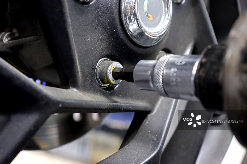 摩托车修理工的手特写，使用气动扳手在机械车间紧固螺母图片素材