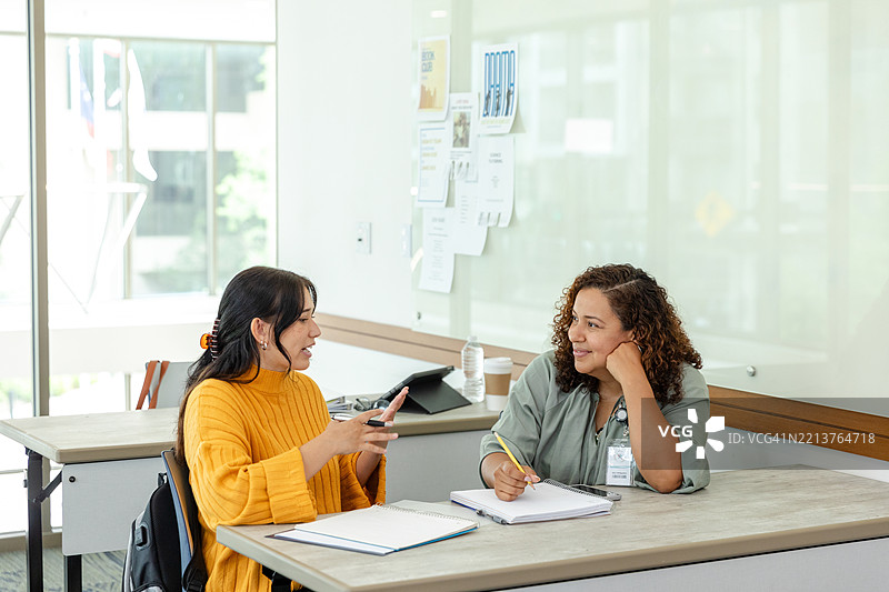 两位穿着休闲服的女性在教室里讨论图片素材