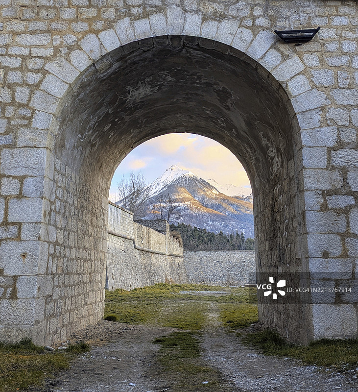 石拱门，背景是小路和山脉，营造出宁静的氛围。法国布里扬松，欧洲图片素材