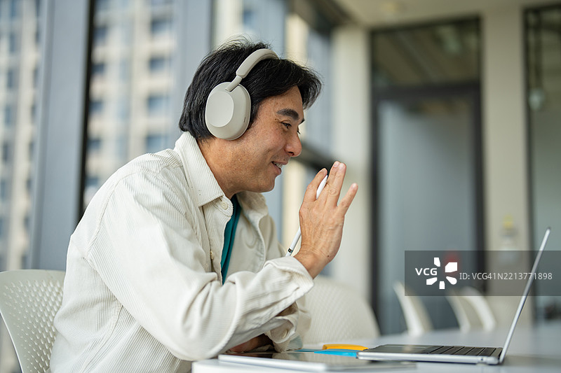 男性员工在办公室通过视频通话与多元化的同事进行在线简报，手边有笔记本电脑。图片素材