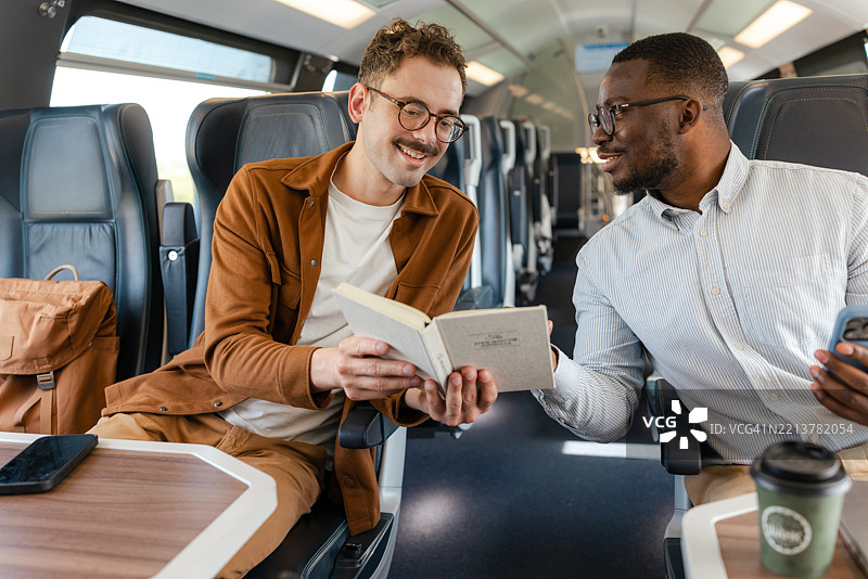 两个朋友在现代列车上享受书籍和咖啡的时光图片素材