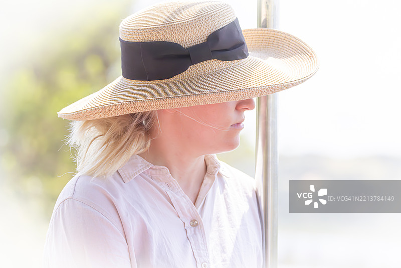 戴着太阳帽的游客摄影师在科西湾的船上游览图片素材