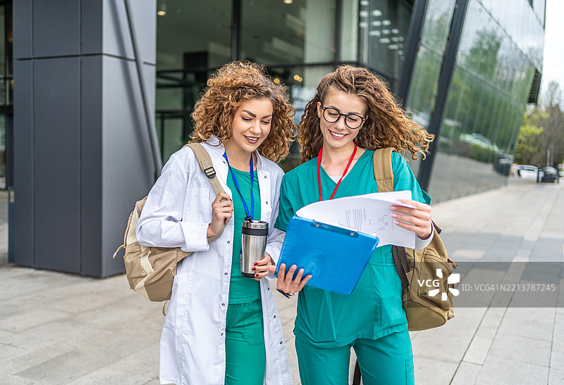 两位年轻护士在医院外讨论病历图片素材