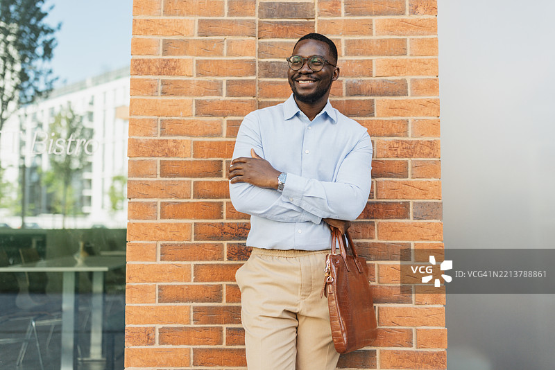 微笑着靠在墙上的自信男人图片素材