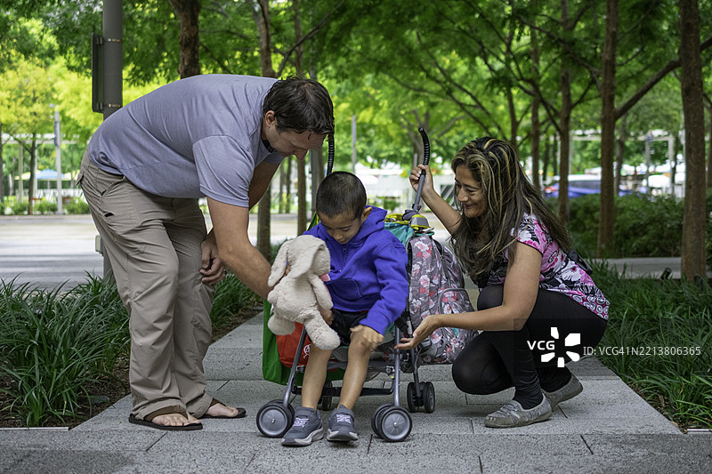 父母帮助小孩从婴儿车里出来图片素材