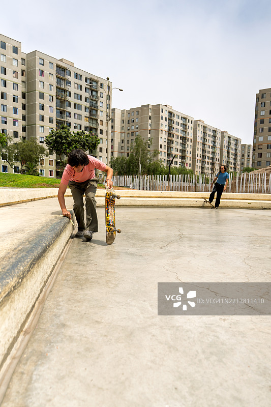 年轻的滑板少年将滑板放在滑板公园的边缘上图片素材