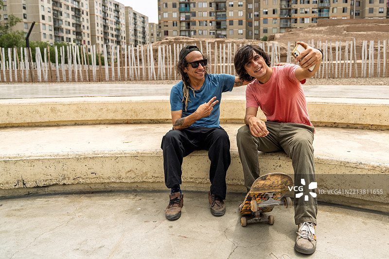 两名快乐的滑冰者在华卡普克亚滑板公园练习后自拍图片素材