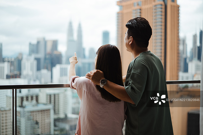 亚洲情侣在家阳台上谈论他们的梦想和未来。图片素材