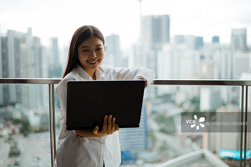 亚洲女性自由职业者在家阳台上使用笔记本电脑工作图片素材