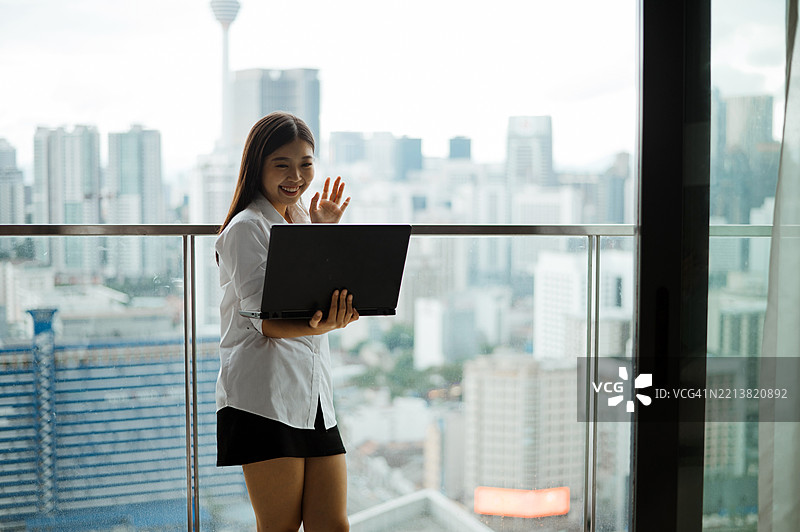 亚洲华裔女性在家阳台上使用笔记本电脑进行在线会议图片素材