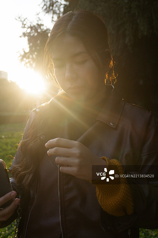 一位女性在日落时分拿着智能手机图片素材