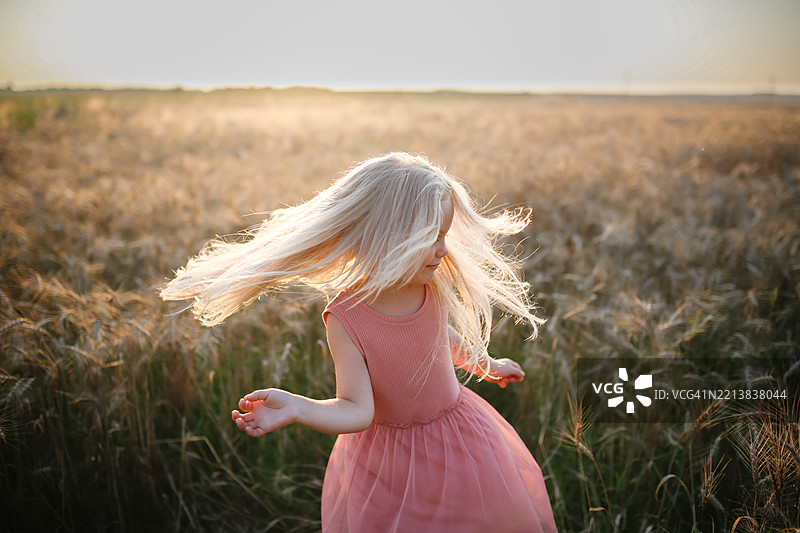 金发女孩在金色麦田中舞动，展现出自由与快乐的精神。图片素材