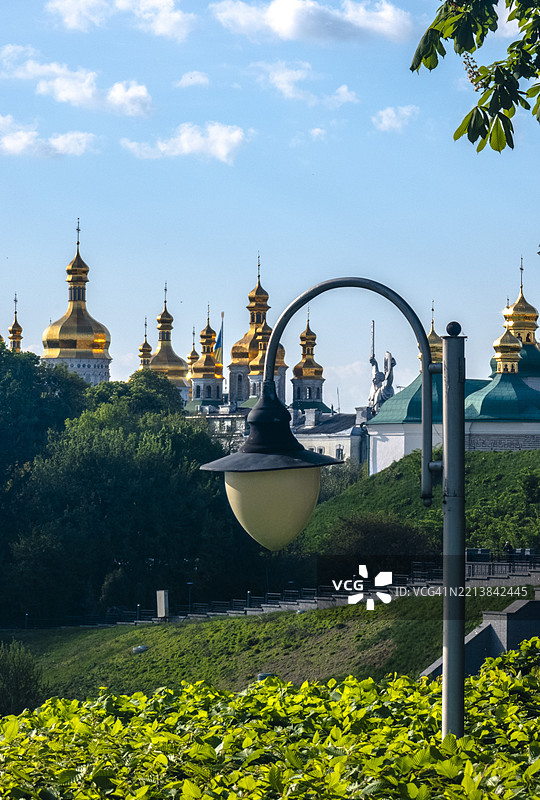 乌克兰母亲纪念碑在基辅拉夫拉修道院金色圆顶的衬托下巍然屹立，天空湛蓝。图片素材