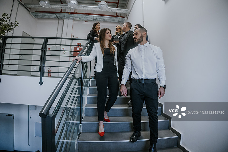 一群专业人士在现代办公室的楼梯上讨论图片素材