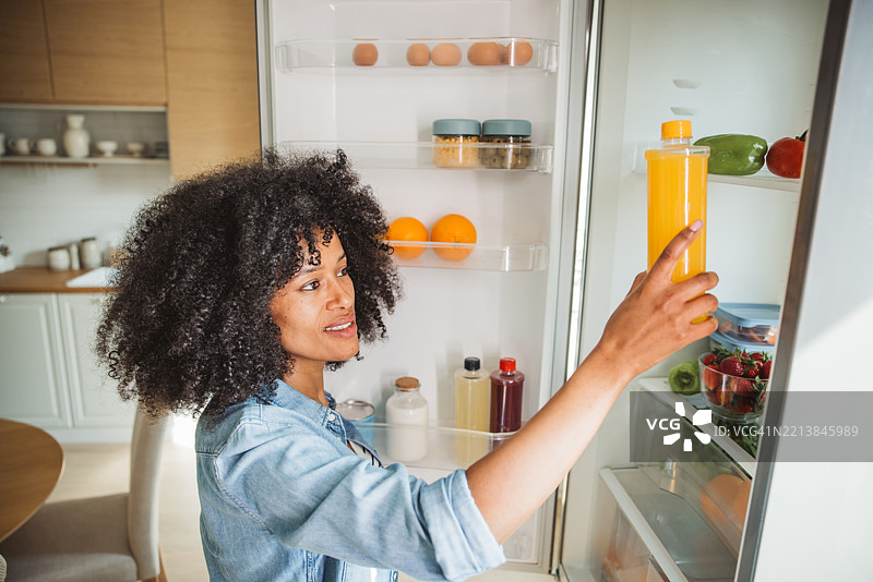 女人从装满杂货的冰箱里拿果汁图片素材