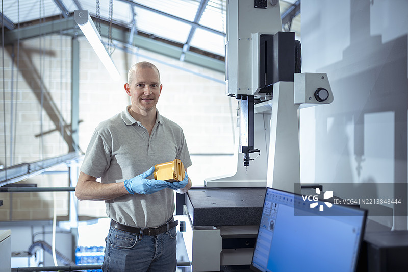 工程师在小型工程厂房中手持金属零件的肖像图片素材