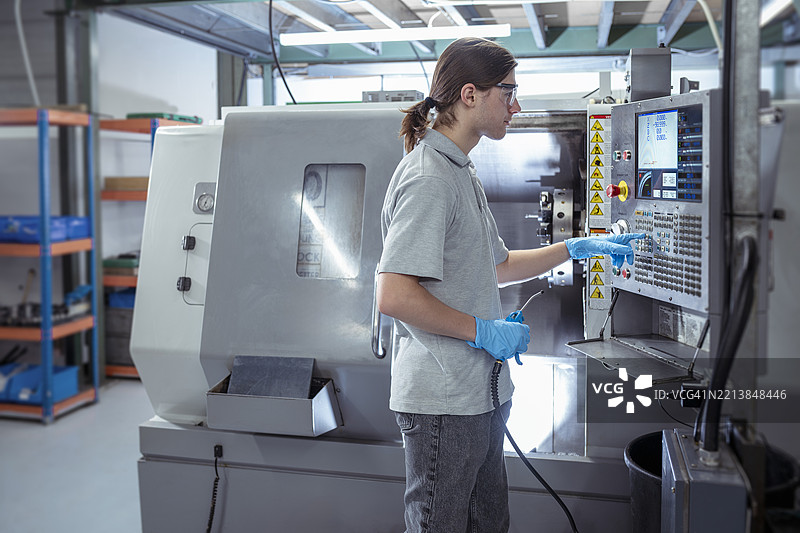 小型工程厂的学徒工程师操作数控车床图片素材