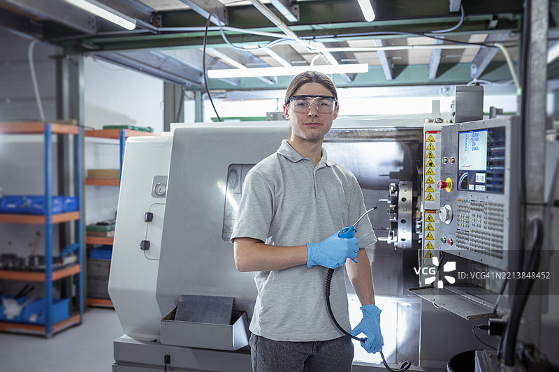 小型工程厂中使用数控车床的学徒工程师肖像图片素材