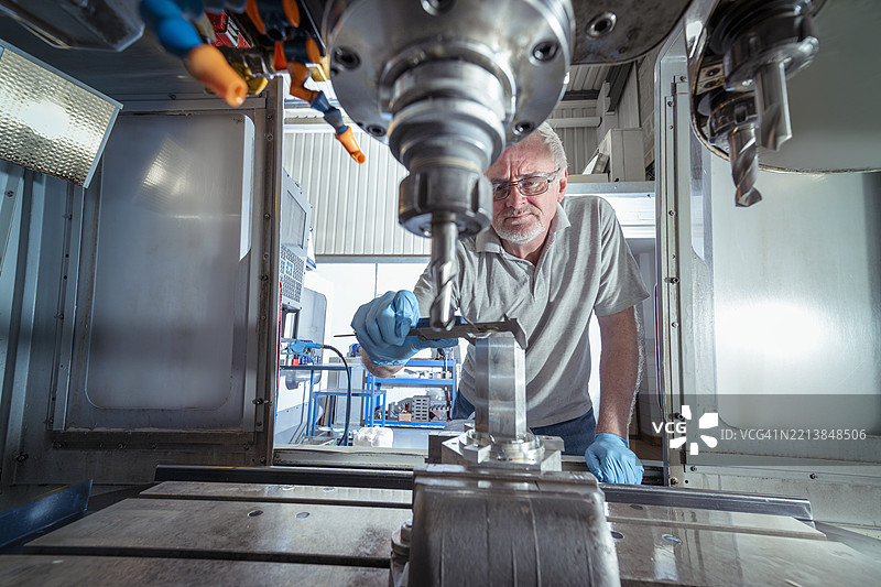 工程师在小型工程厂的数控车床上测量零件图片素材