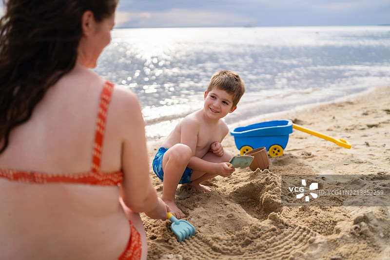 母亲和儿子在海滩上玩沙子图片素材