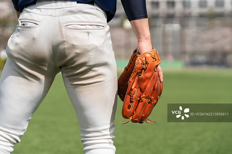 在绿色球场上，棒球运动员手持手套参加户外比赛图片素材