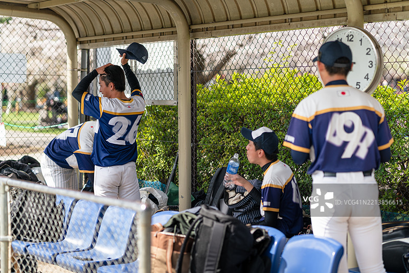 棒球队成员在阳光明媚的比赛日放松于休息区图片素材