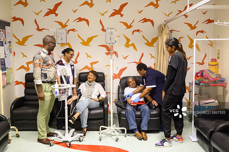 医疗团队在装饰明亮的房间里协助患者进行化疗癌症治疗图片素材